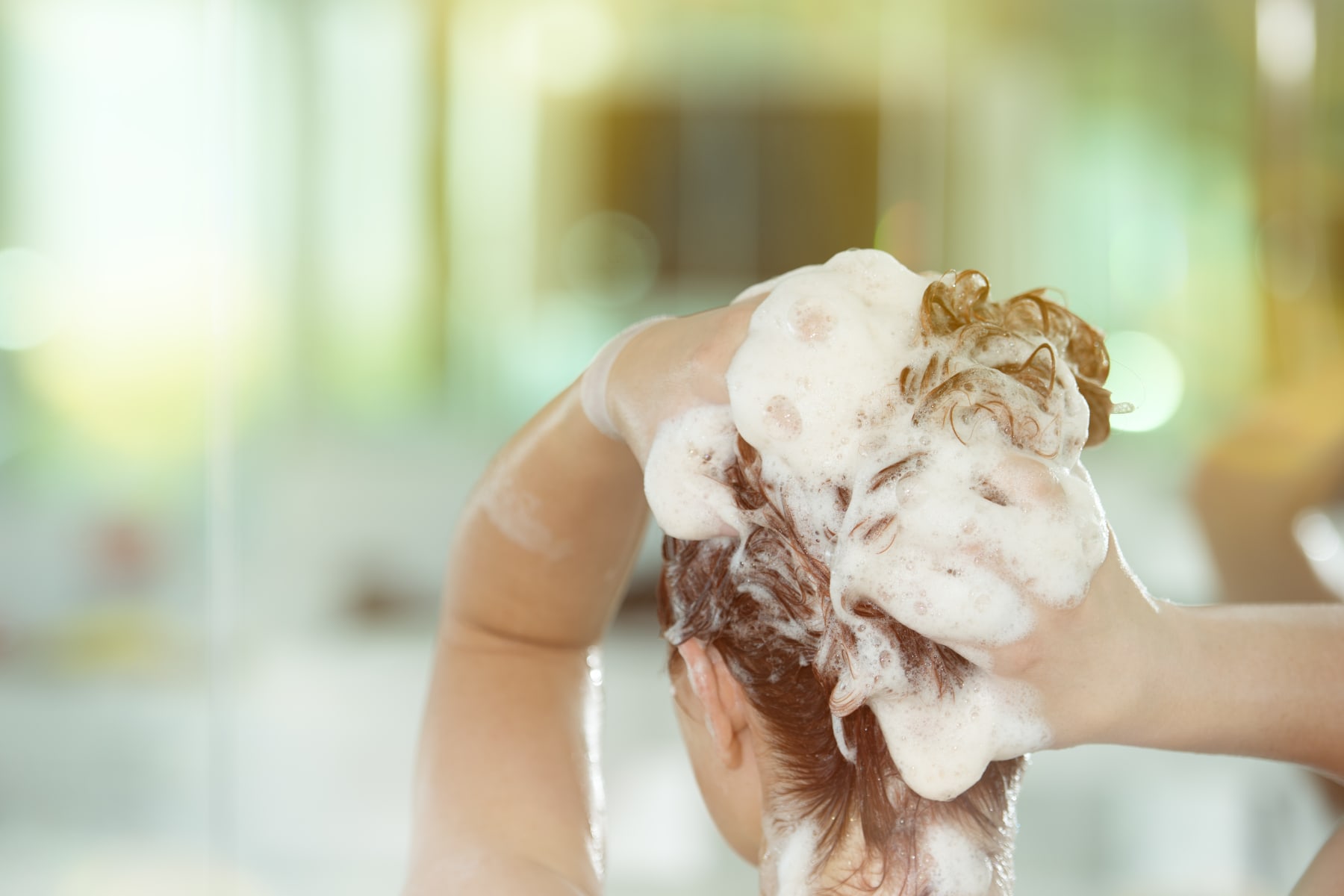 Woman uses hands to wash hair.