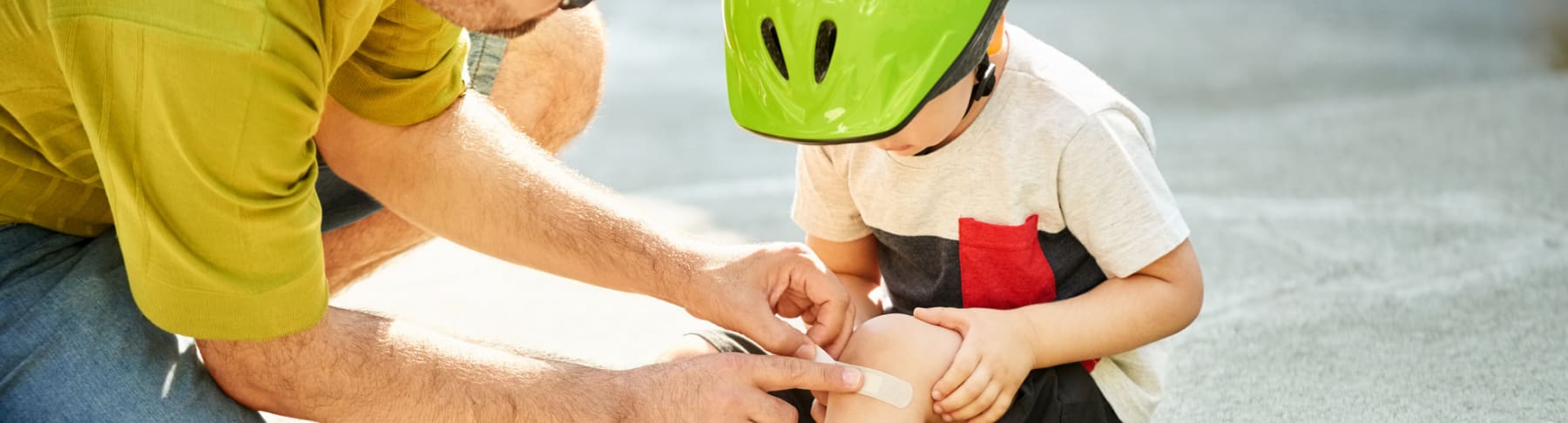Father puts bandage on child's knee.