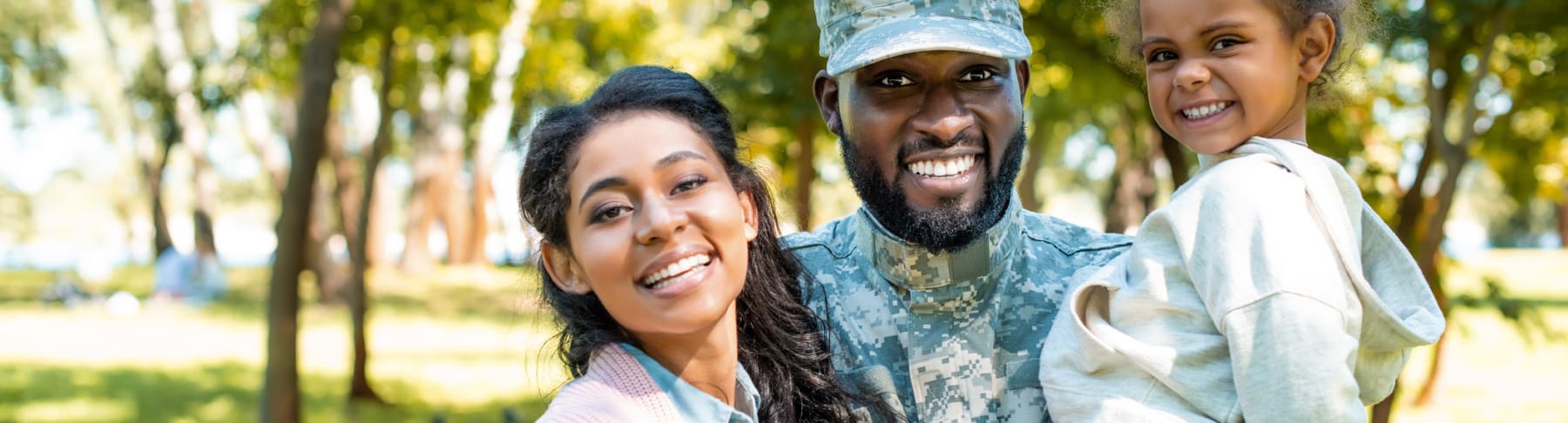 Military family smiles in nature setting.