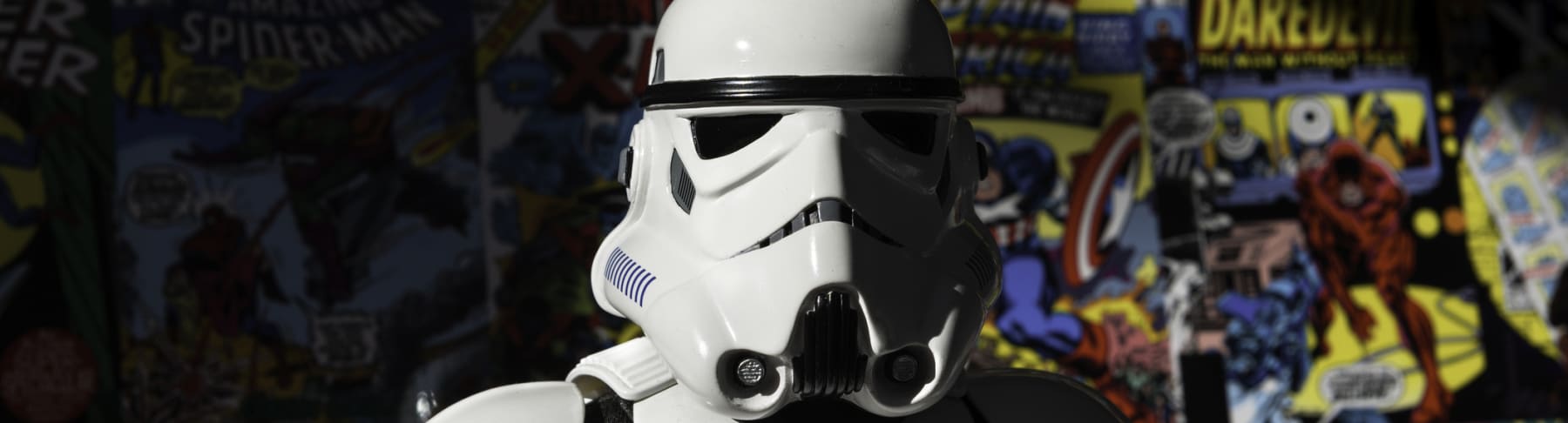 Star Wars Stormtrooper action figure stands in front of comic book wall.