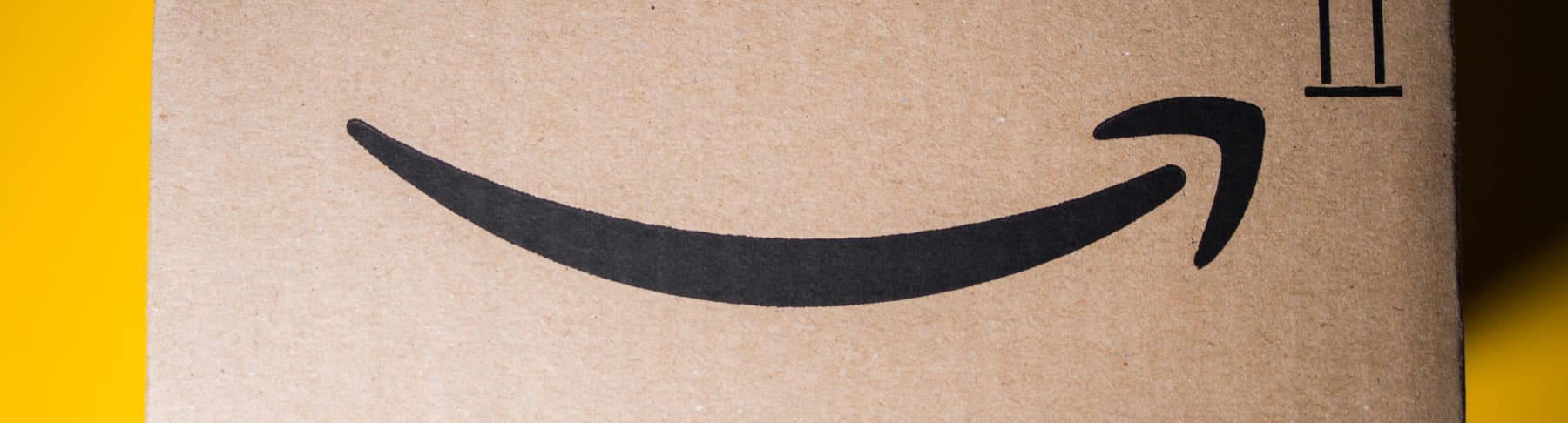Cardboard Amazon box is shown in front of a yellow background.