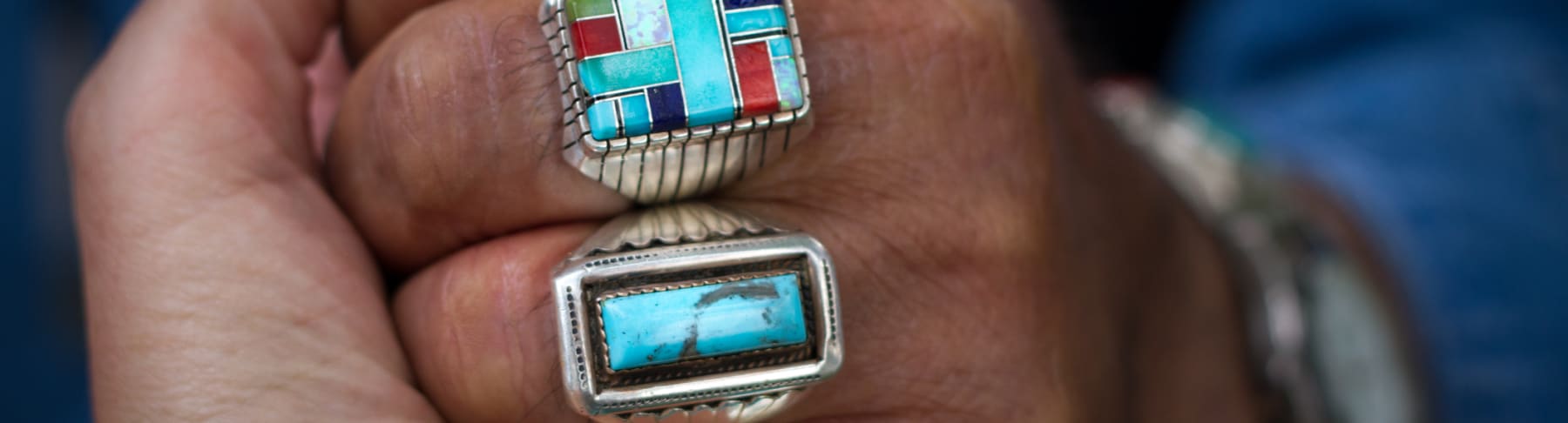 Person holds hand with Native American turquoise rings.