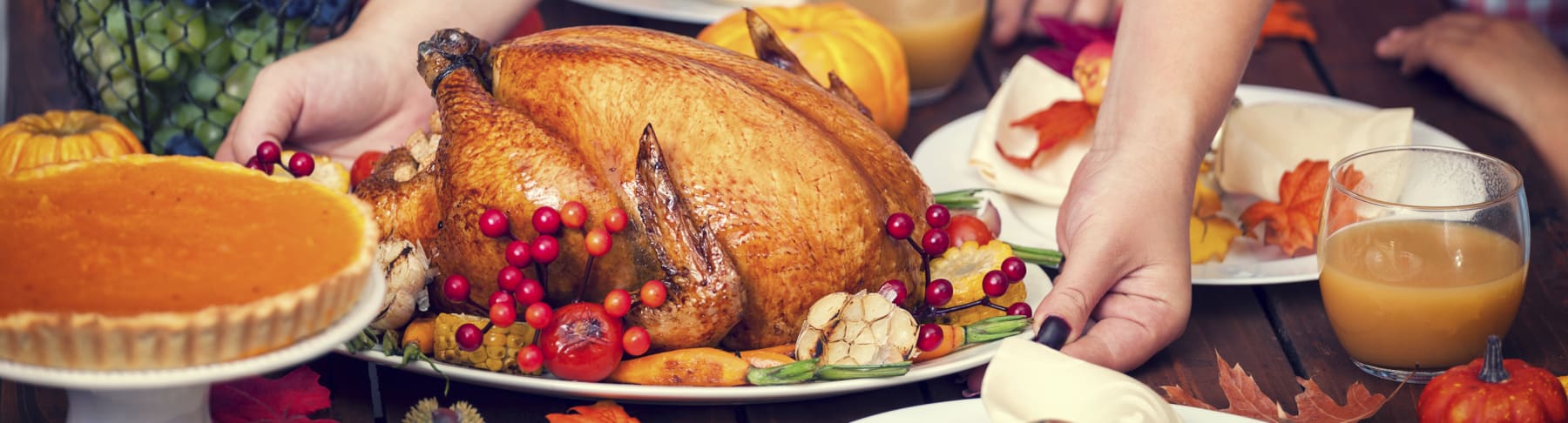 Turkey placed on table decorated for Thanksgiving.