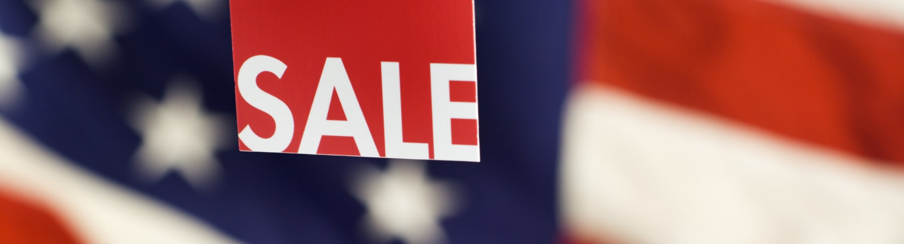 Sale sign hangs in front of American flag.