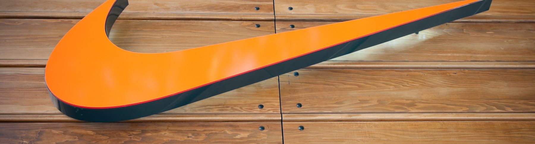 Nike orange swoosh on wooden background.