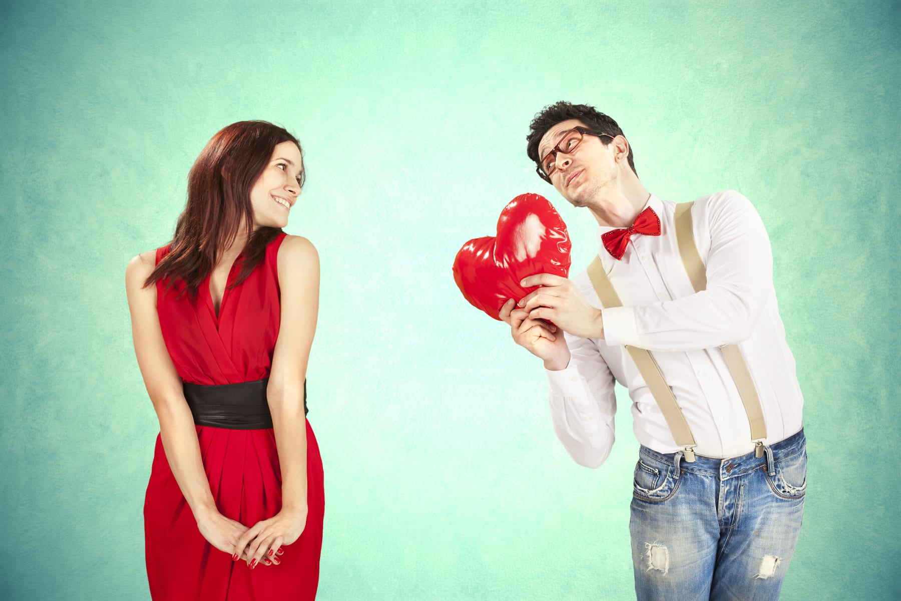 A woman looks at a man holding a heart.