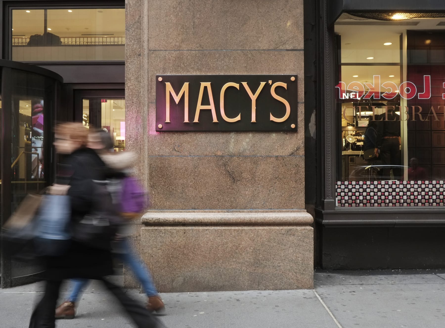People walk past a Macy's sign