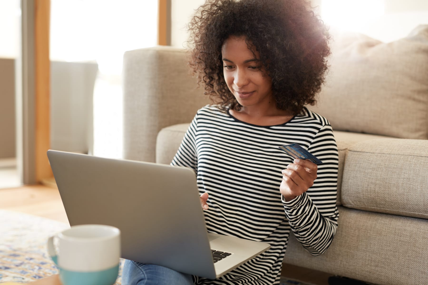 Woman holds credit card while looking at laptop.