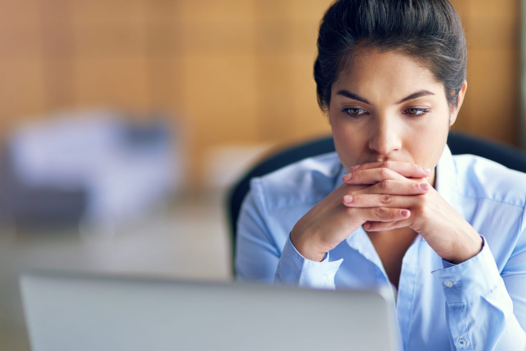 Woman sits at computer and thinks.