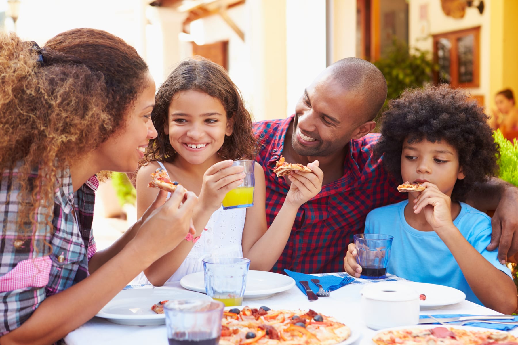 Family eats pizza together at outdoor restaurant.