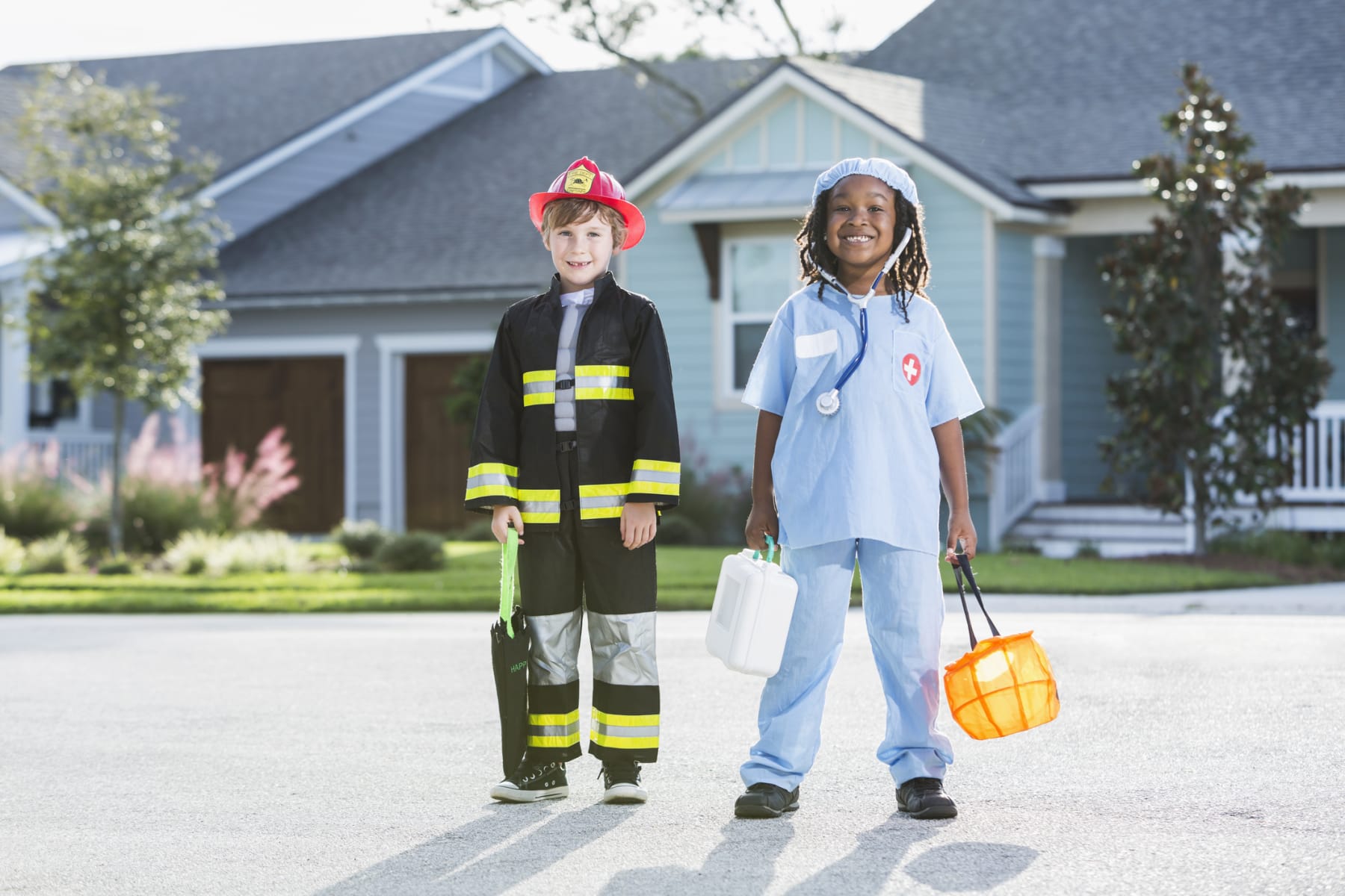Children in Halloween costumes stand on residential street.