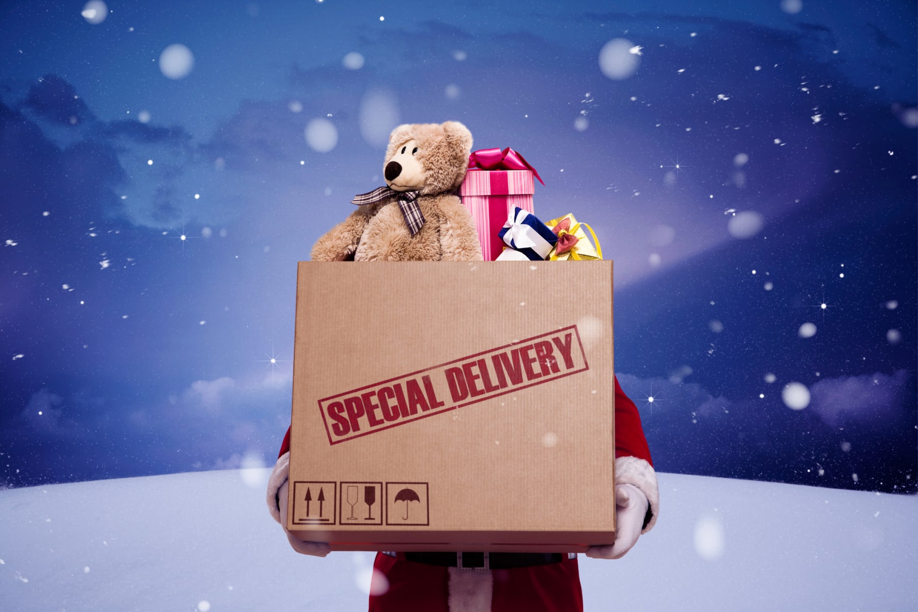 Santa Claus holding a Special Delivery cardboard box filled with toys.