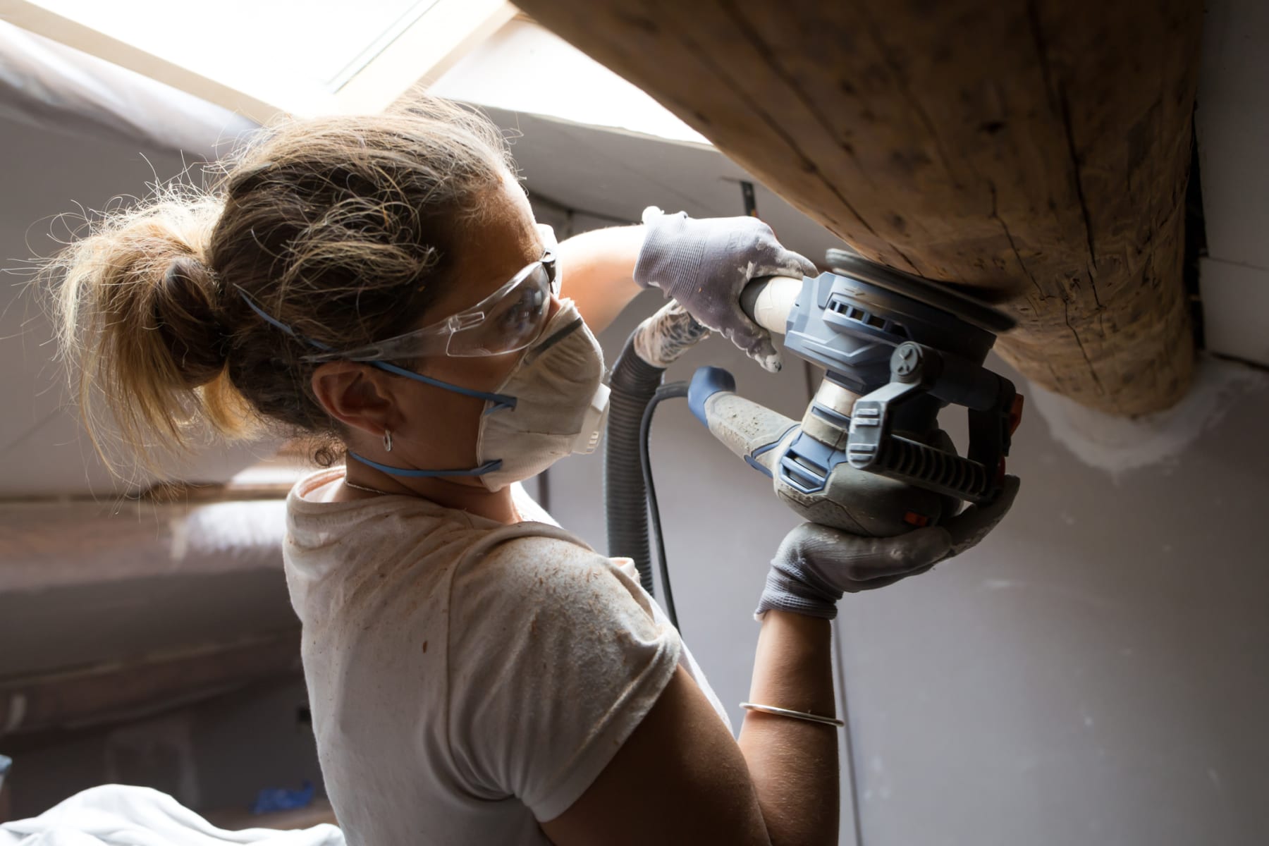 Woman uses power sander for home improvement.