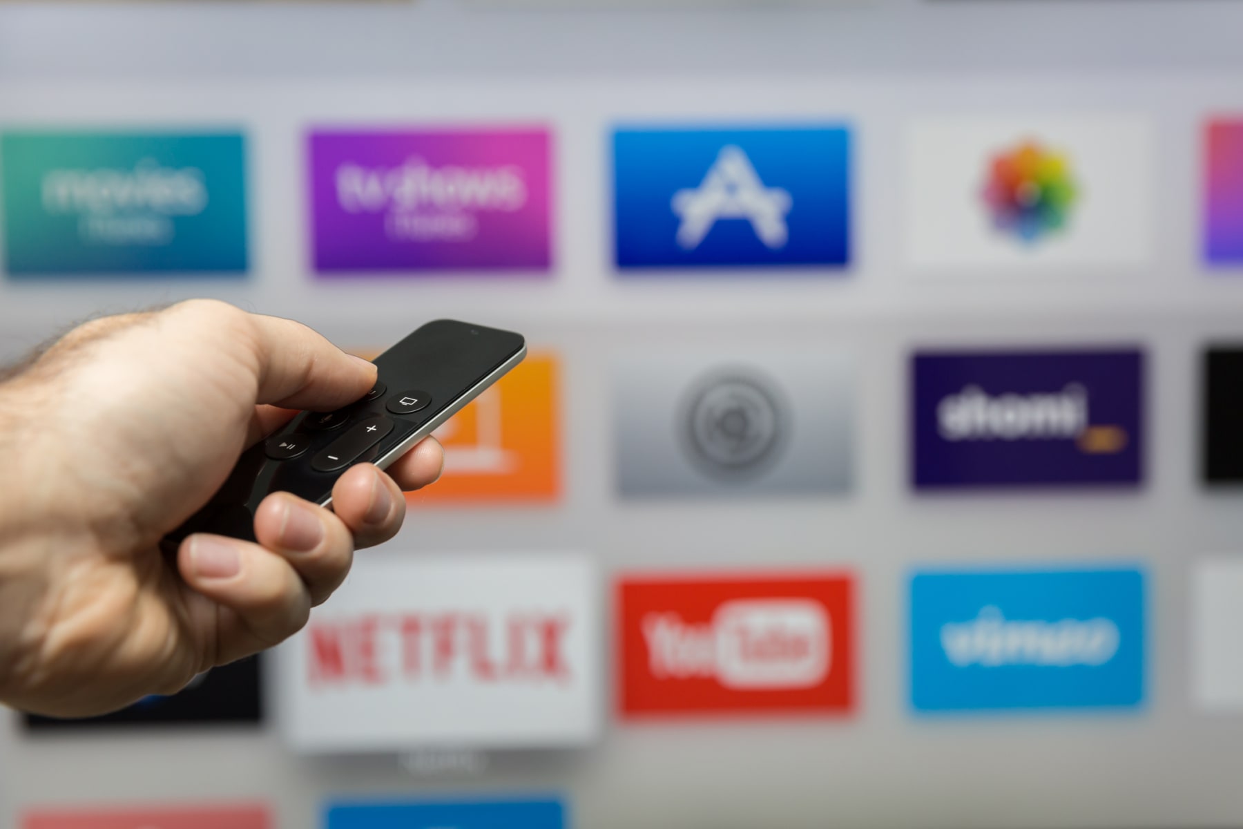 Person holds Apple TV remote and browses channel options.