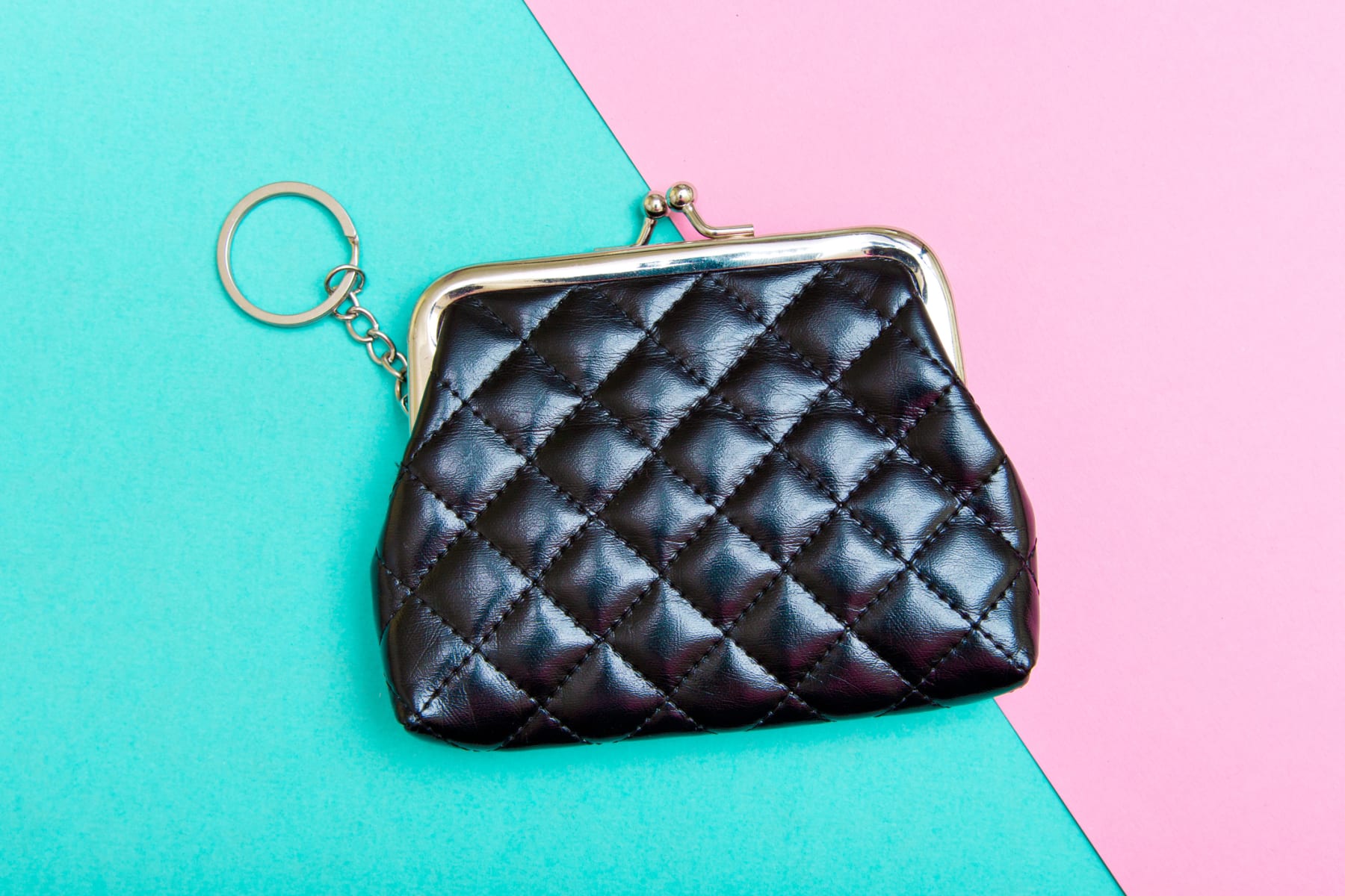 Black coin purse shown against a pink and turquoise background.