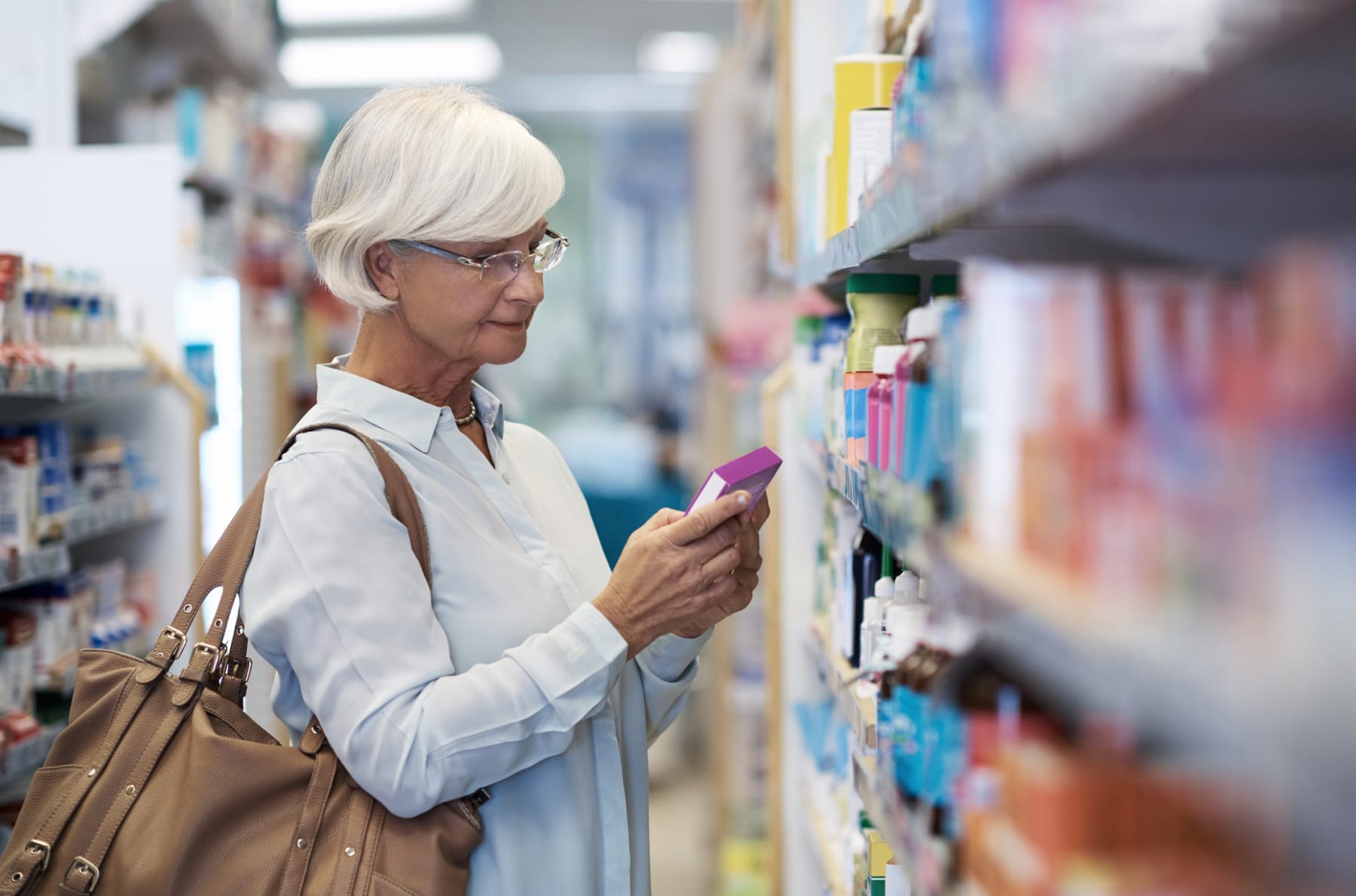 An older woman shops in-store for medication.