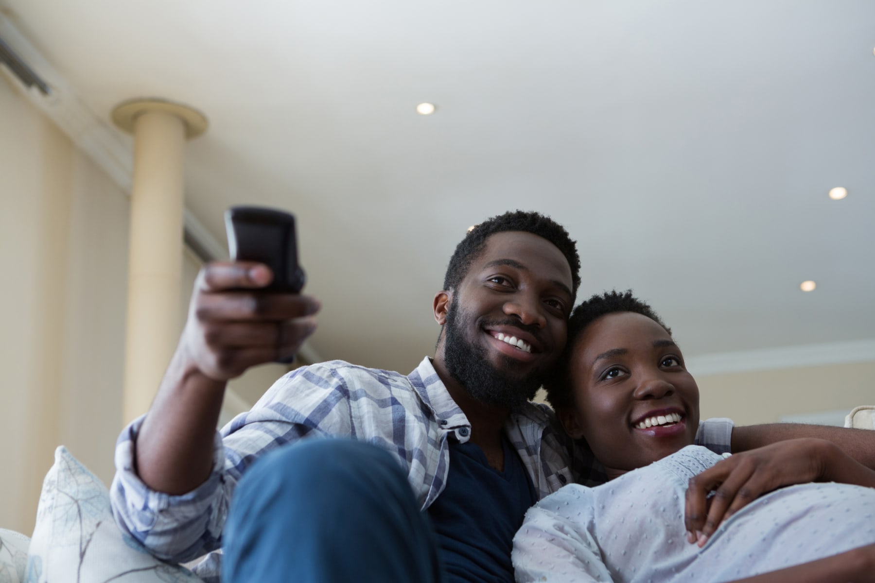 Relaxed couple watches TV in living room.