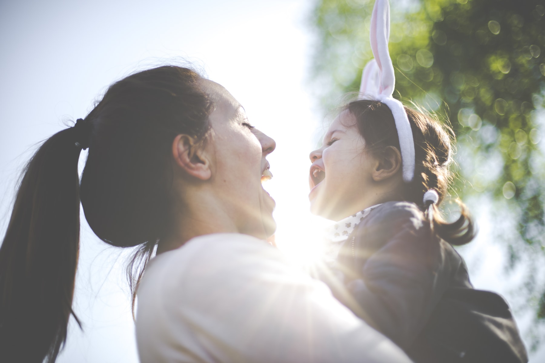 Woman holds child wearing bunny ears.