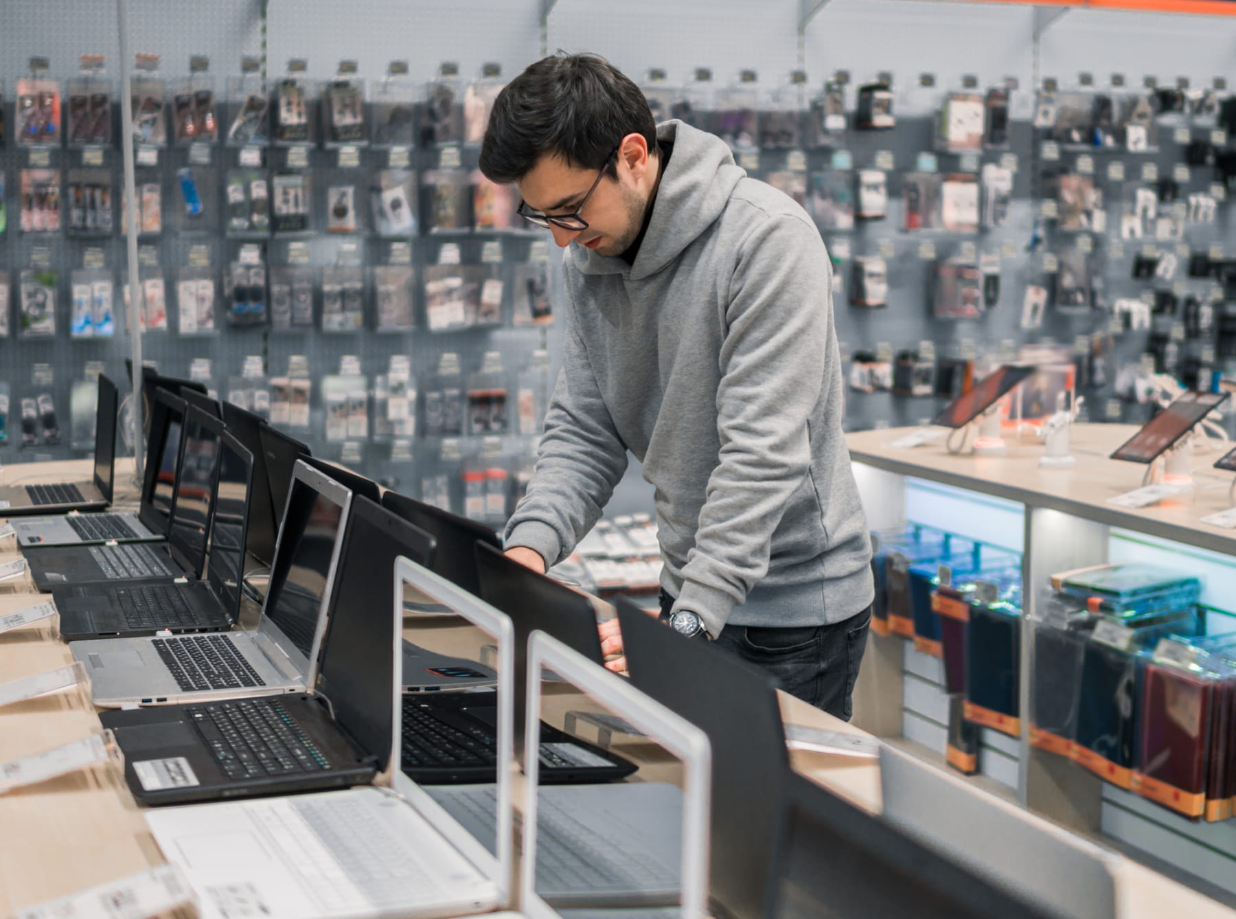 Male customer shops for laptop in electronics store.