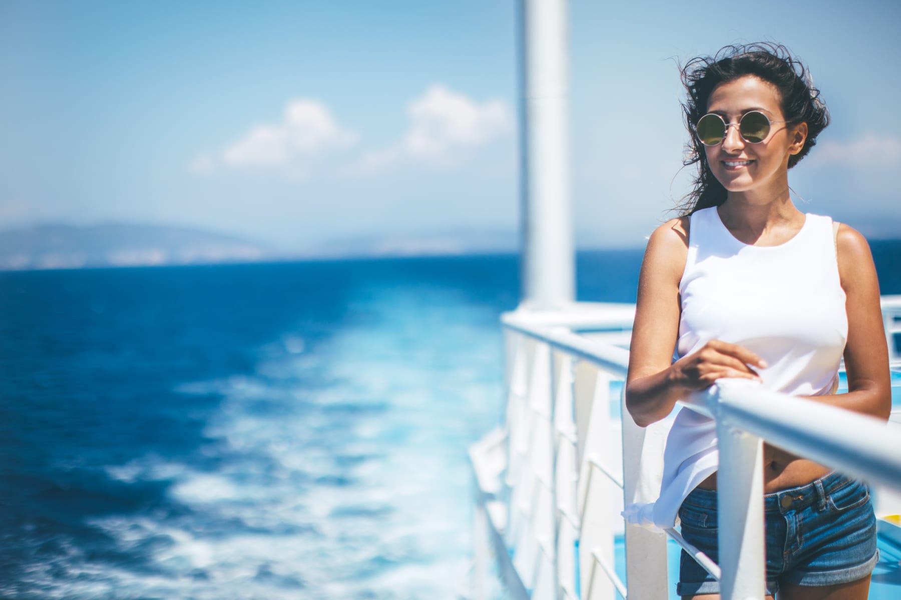 Woman on deck of cruise ship looks out at water.