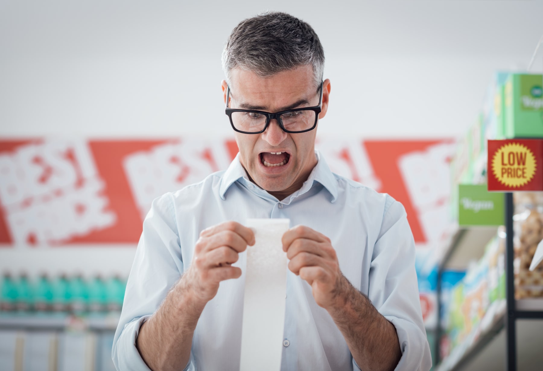 Shocked man looks at receipt in store.