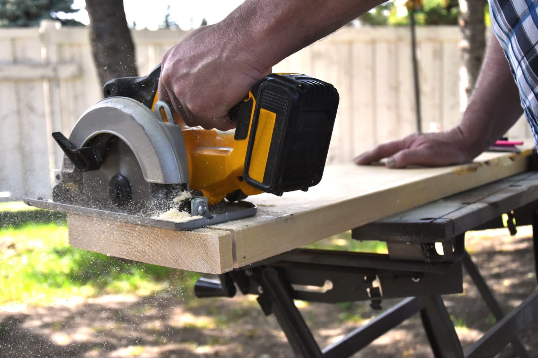 person uses circular saw outdoors