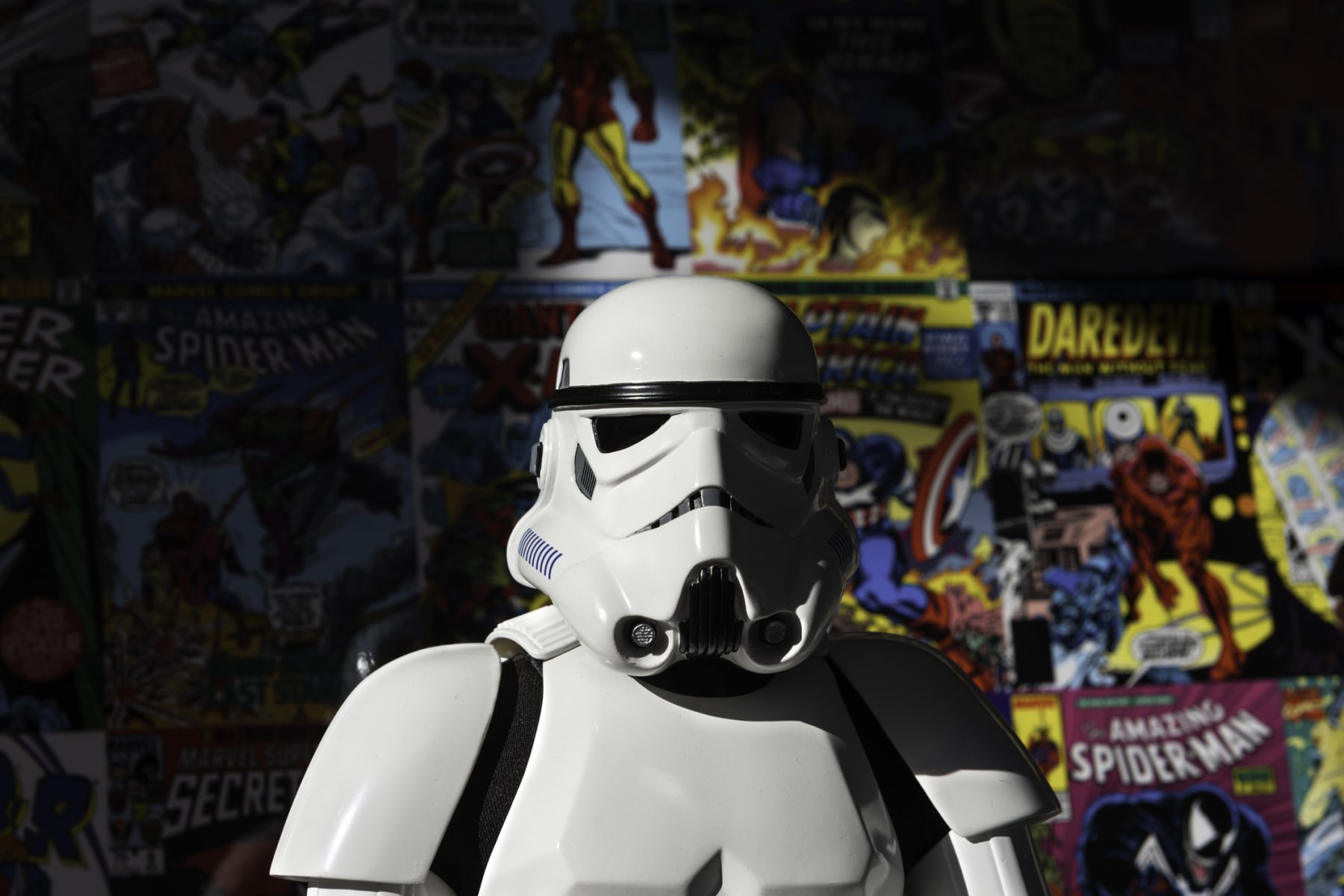Star Wars Stormtrooper action figure stands in front of comic book wall.