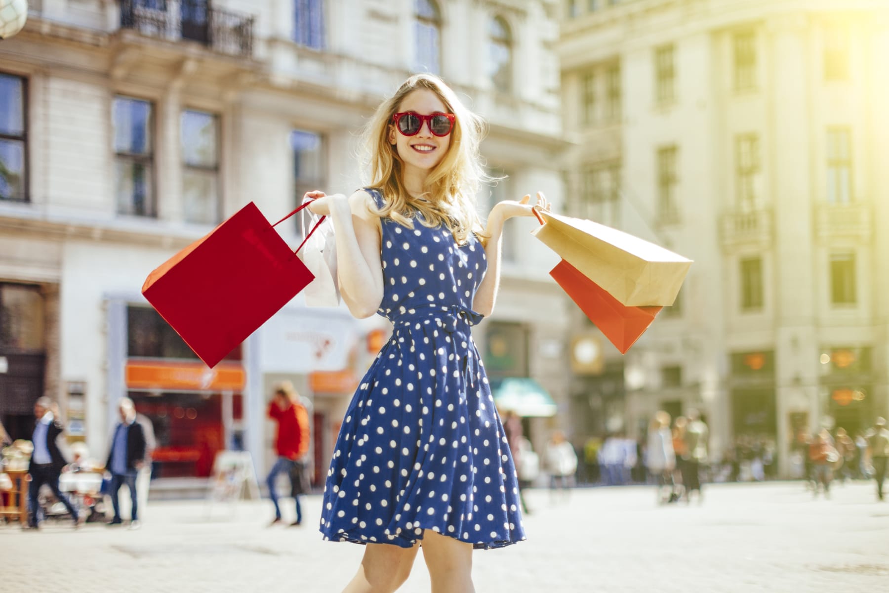 Woman holds shopping bags while walking in city.