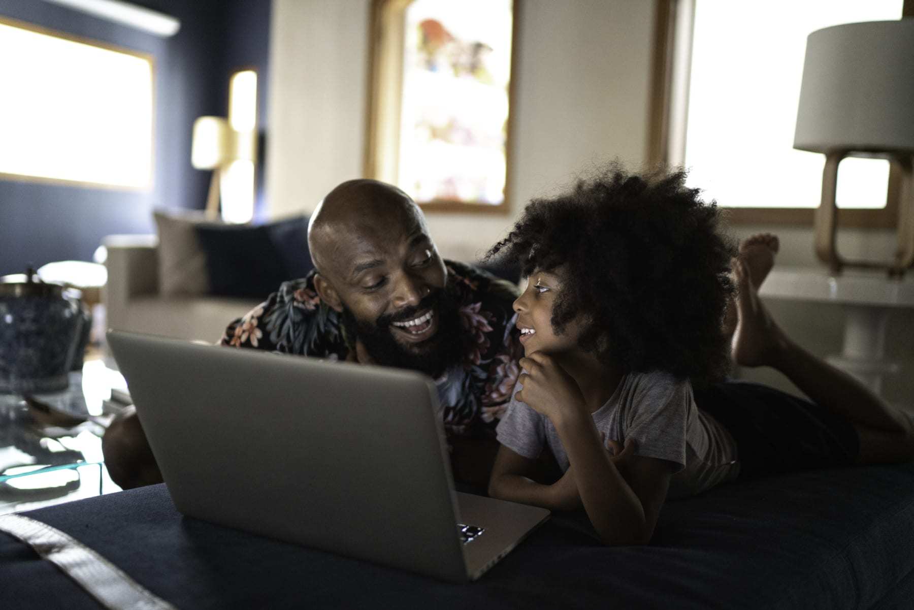 Father and daughter watch movie on laptop.