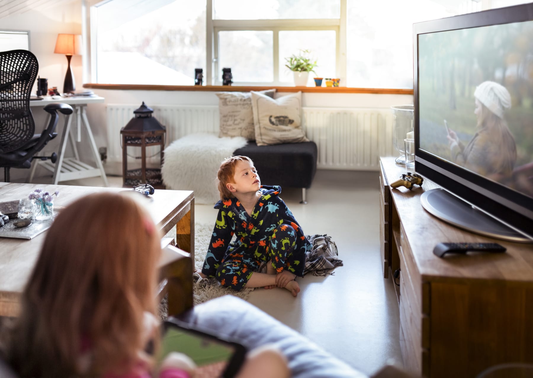 Kid watches TV while sitting on living room floor.