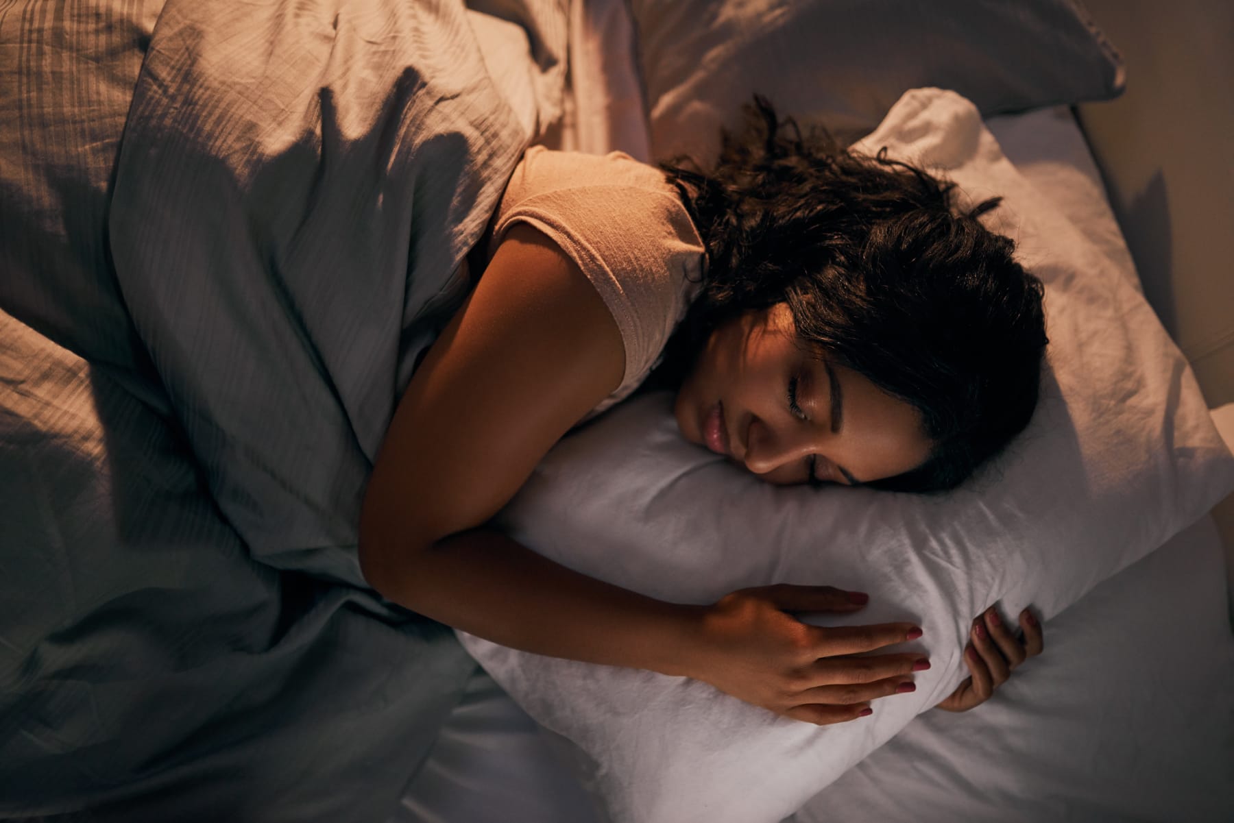 Young woman sleeps on side in bed.