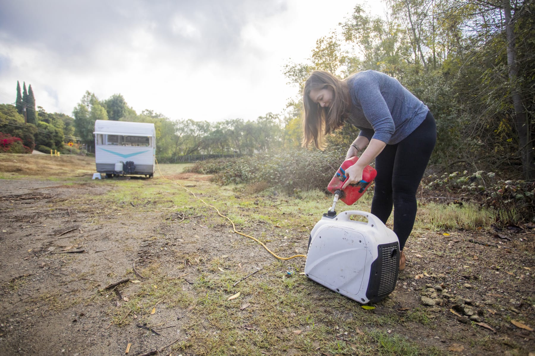 Woman pours gas into generator.