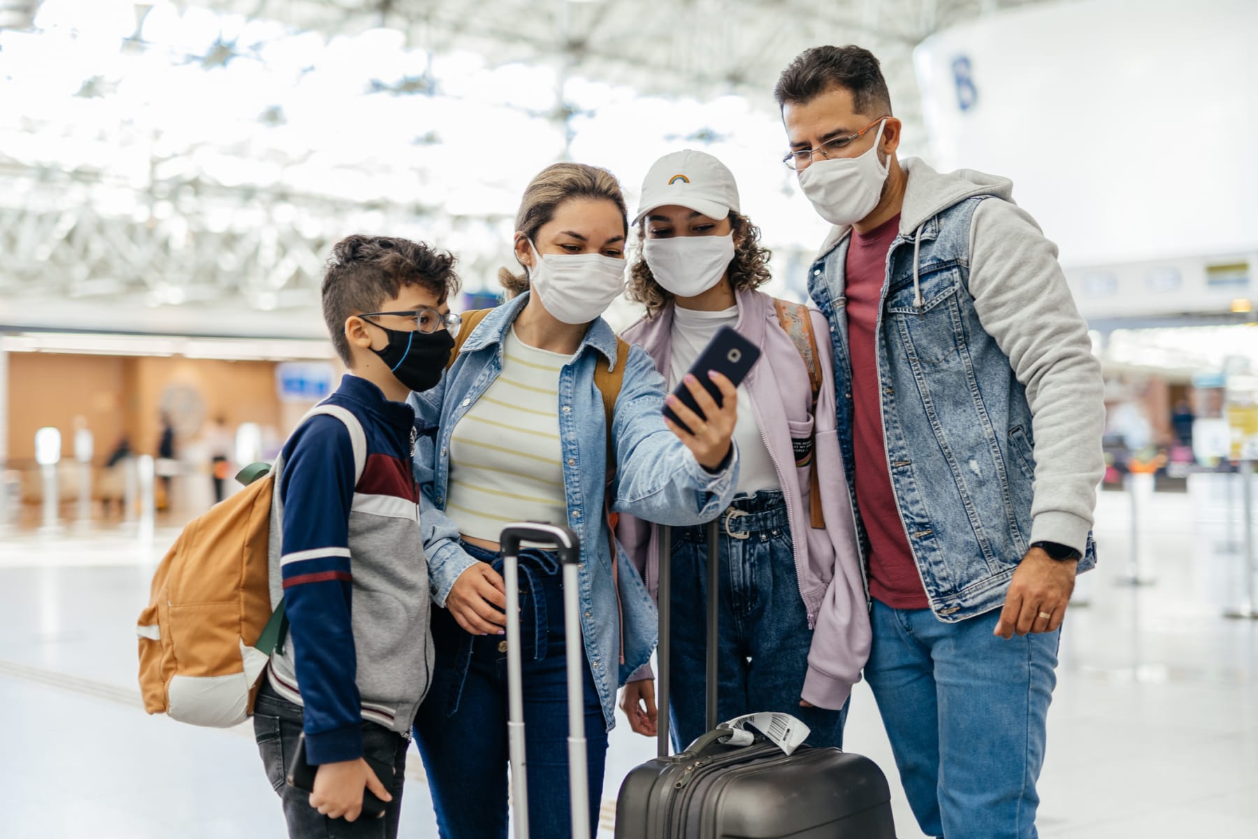 family looks at phone in airport