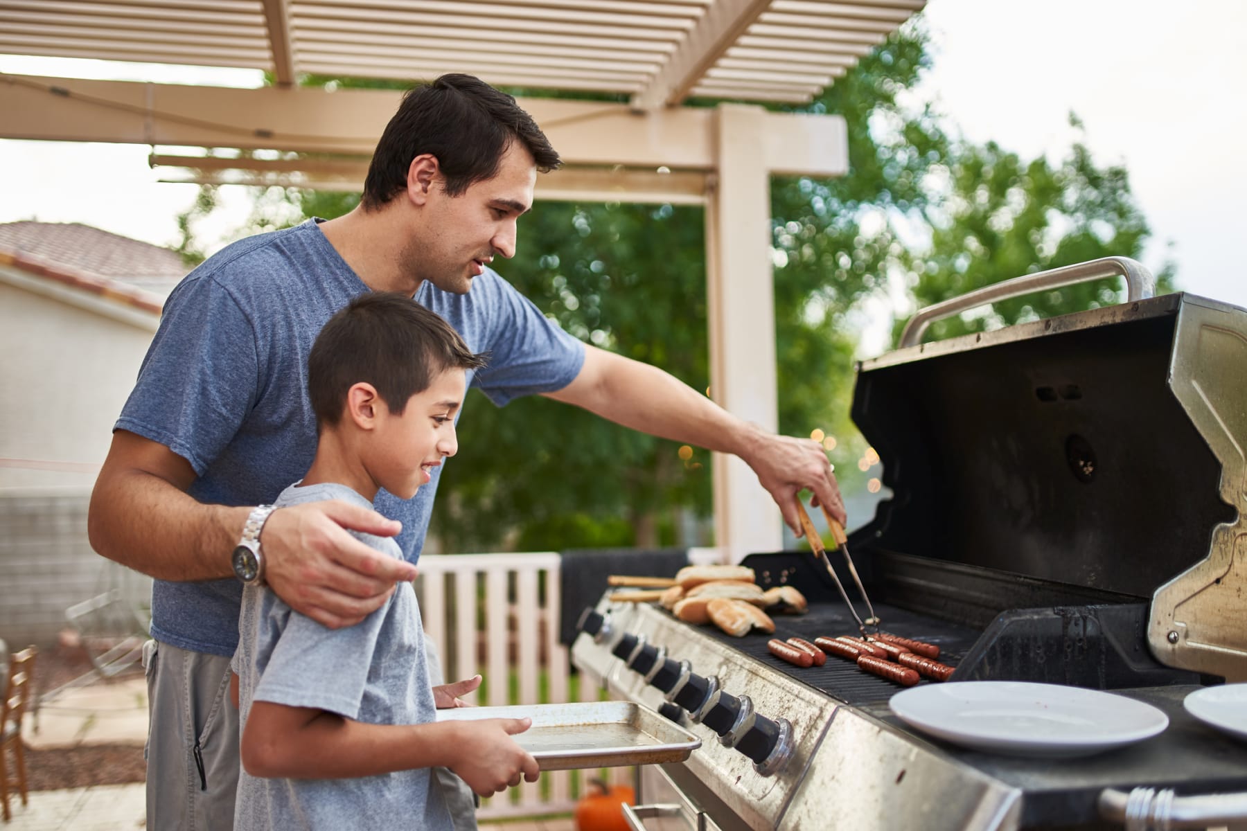 father teaches son to grill