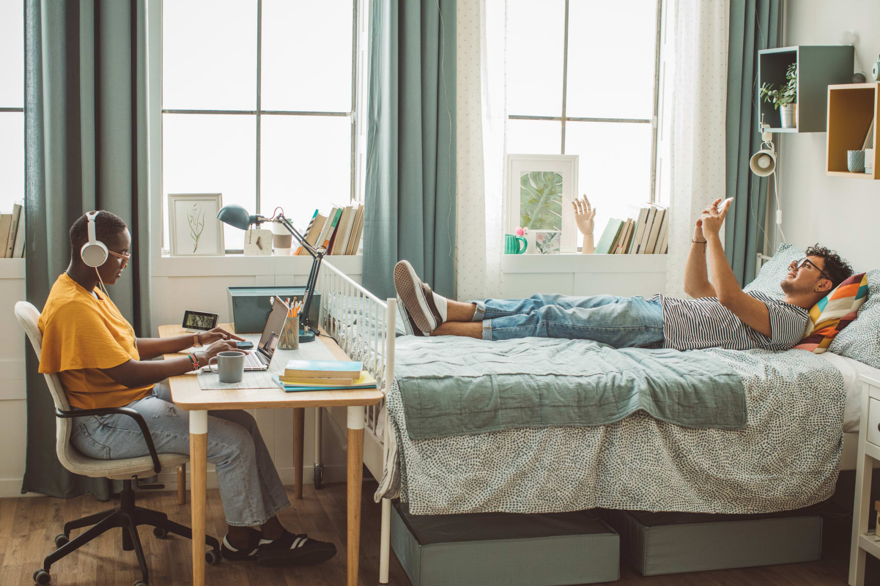 College students study and relax in dorm room.