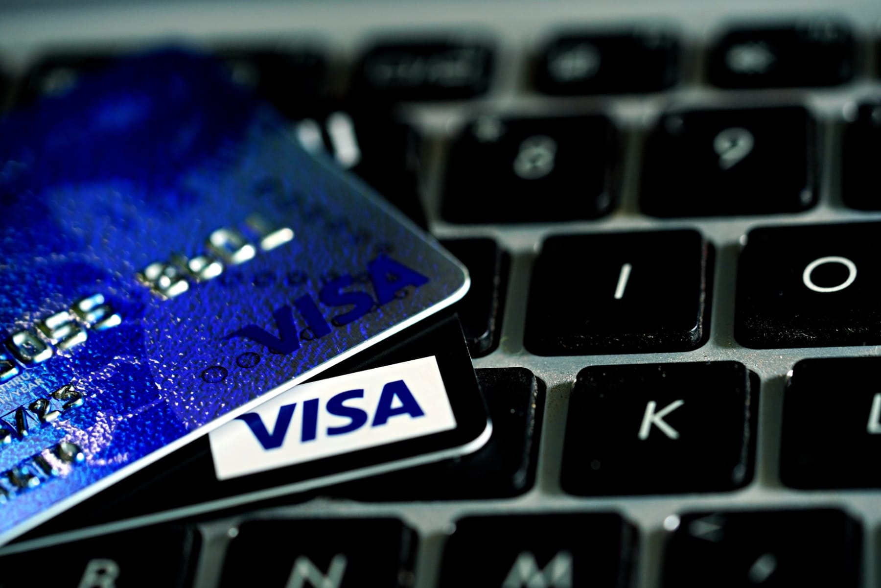 A Visa credit card resting on a computer keyboard for online shopping