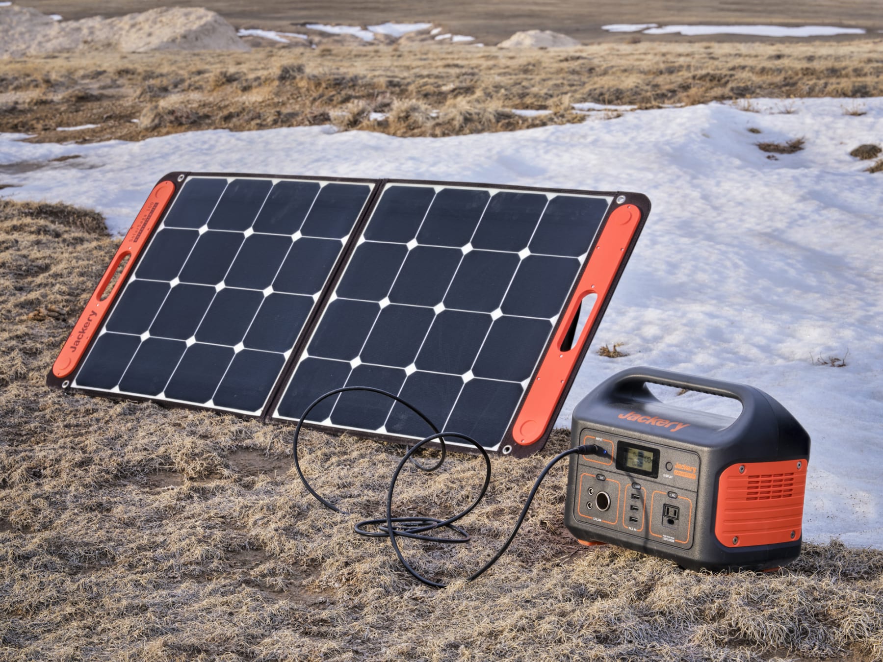 A portable power station and attached solar panel sit in an open field.