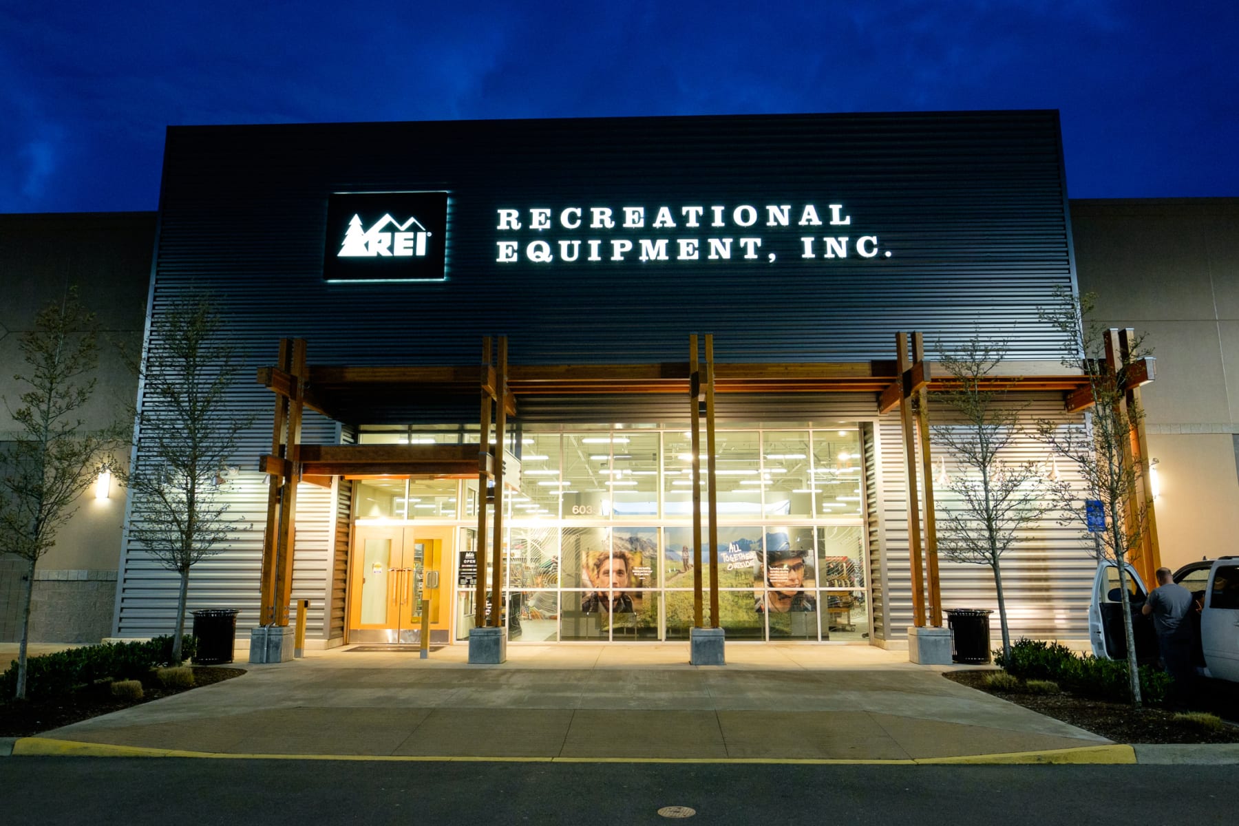 An REI storefront lit up at night.