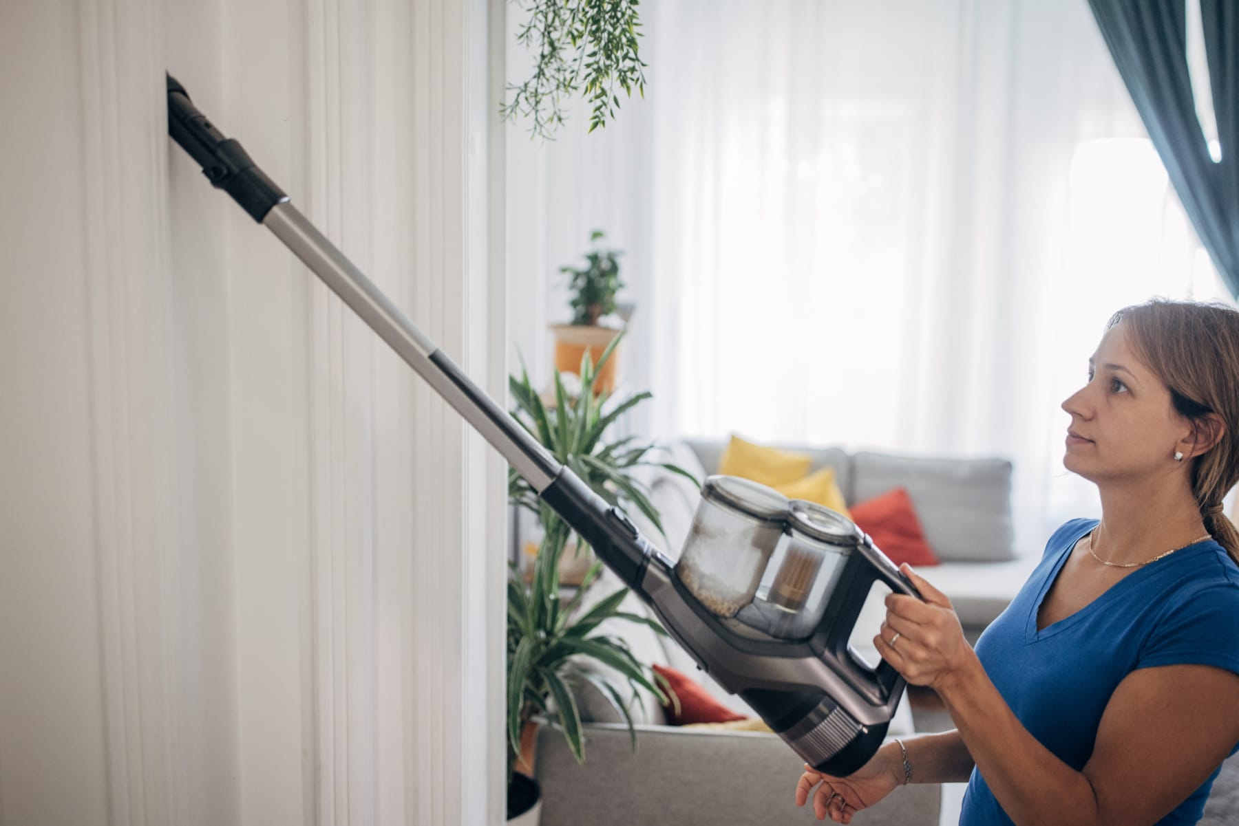 Woman cleans home with cordless stick vacuum.