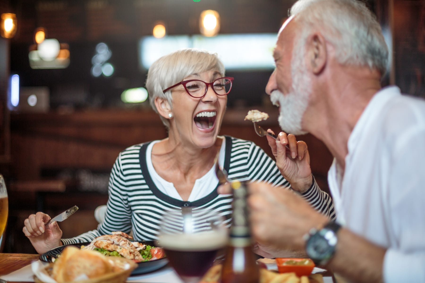 An older couple enjoys dinner together out at a restaurant.