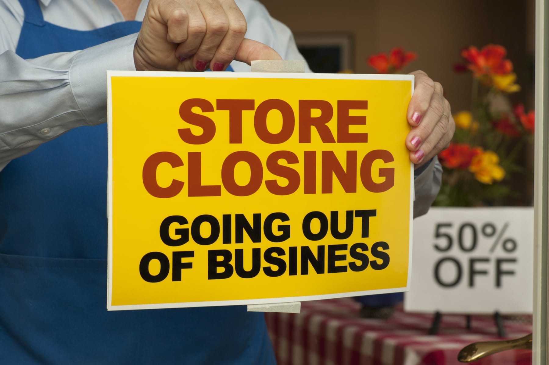 Person places store closing sign on window.