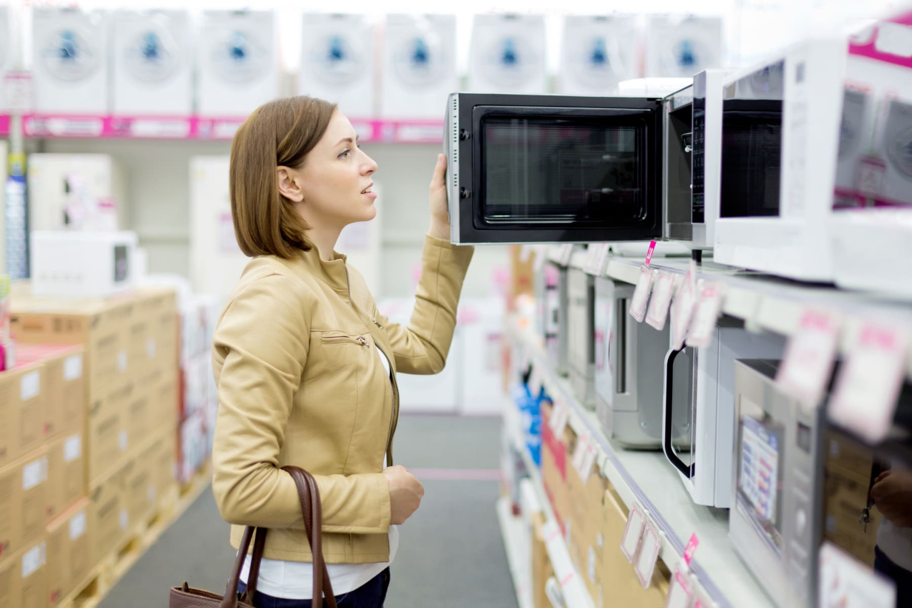 Woman shops for microwaves inside store.