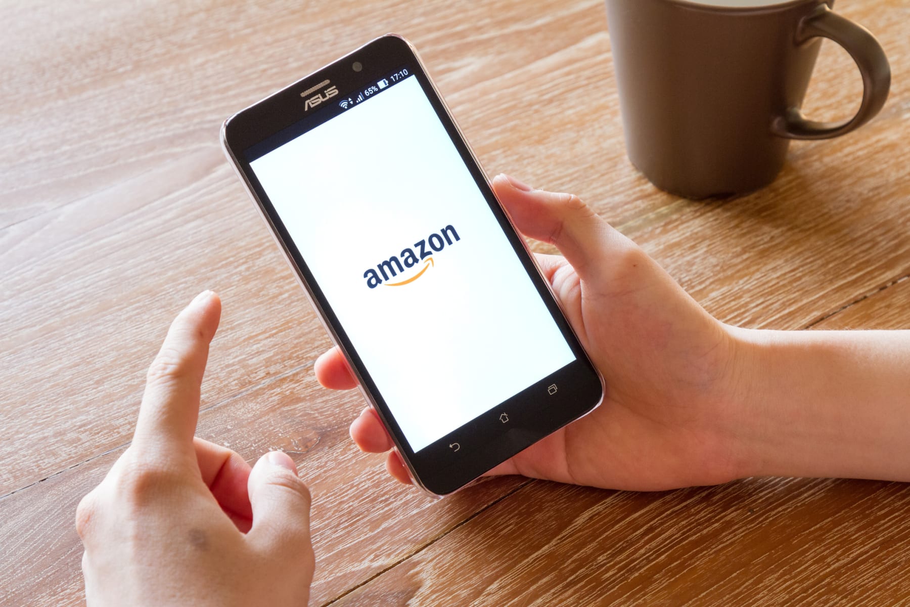 Person holds phone displaying the Amazon logo.