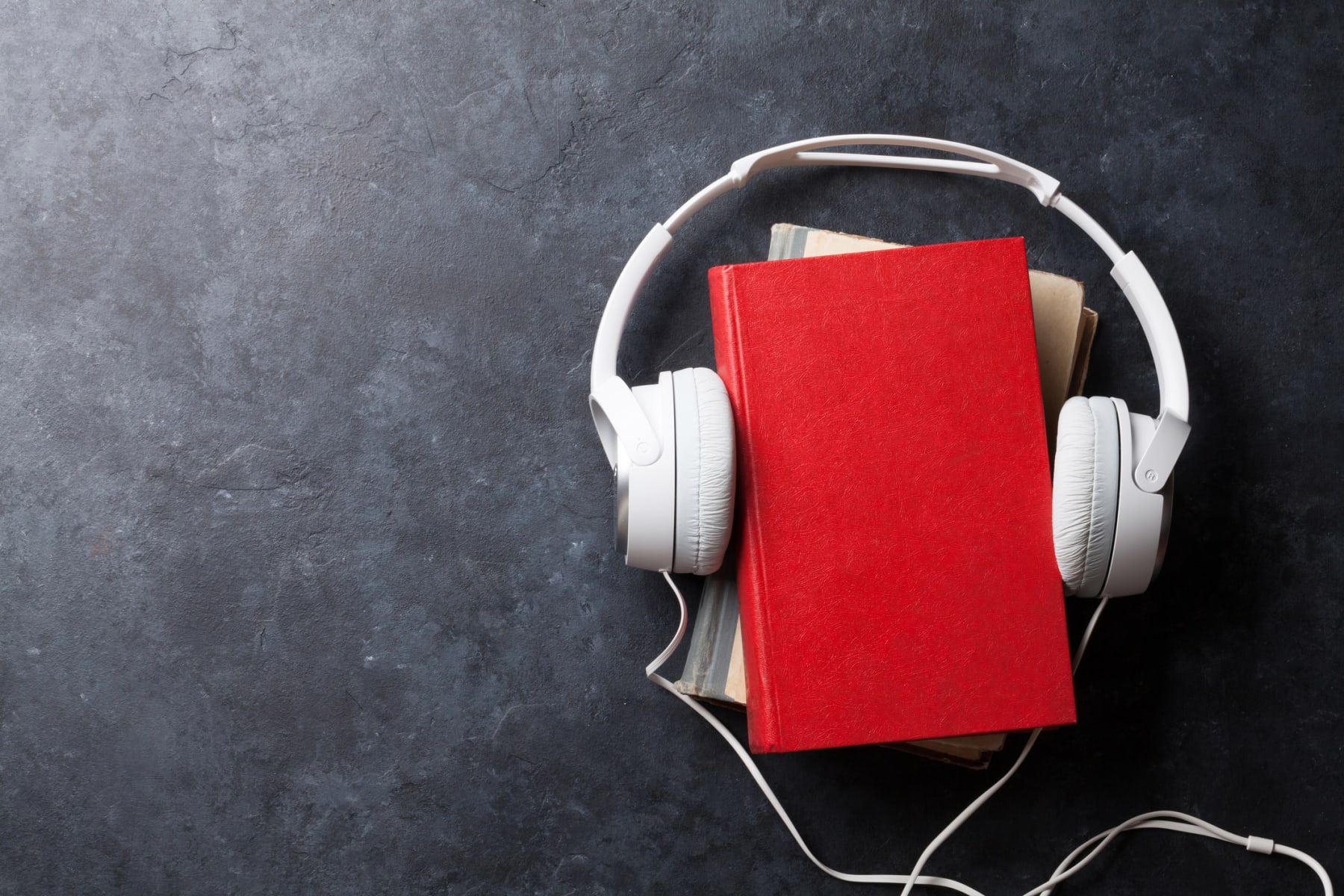 Headphones and books displayed on stone table.