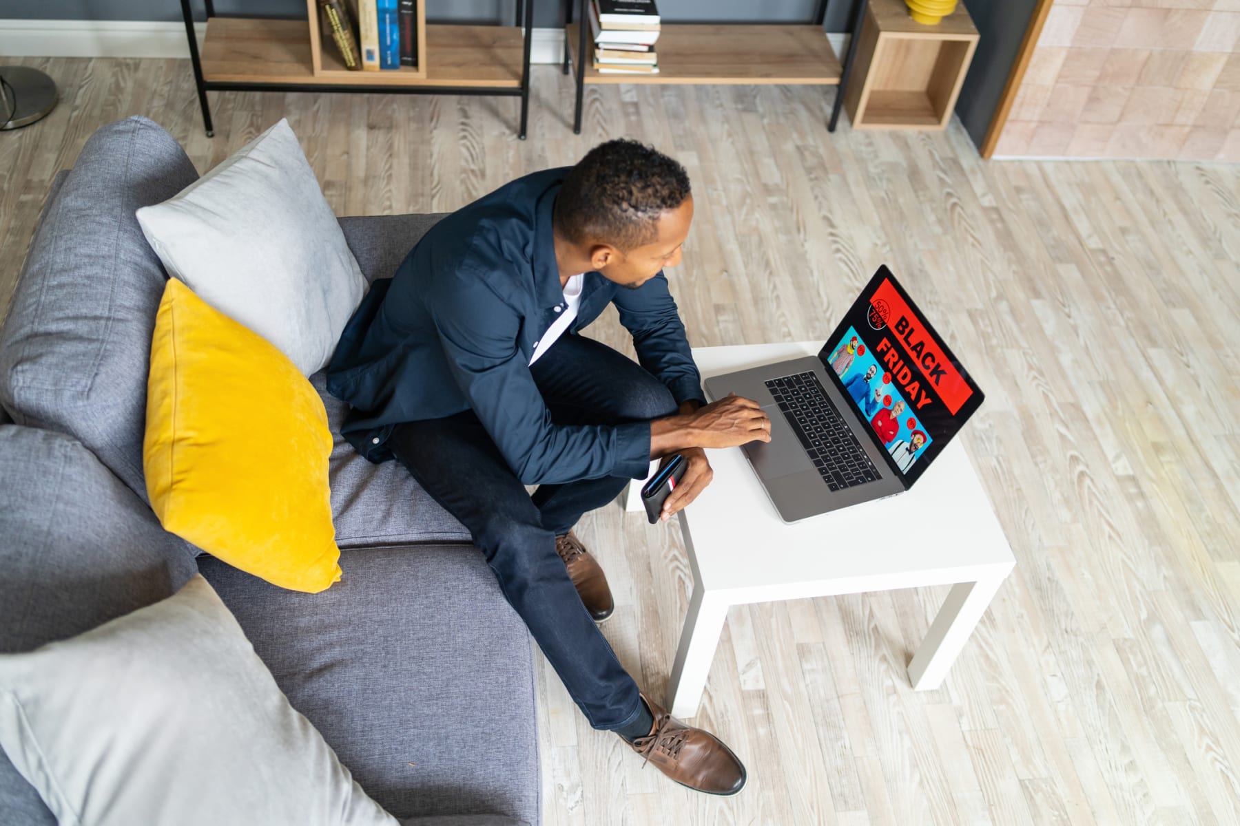 Man does Black Friday shopping on laptop while holding wallet.