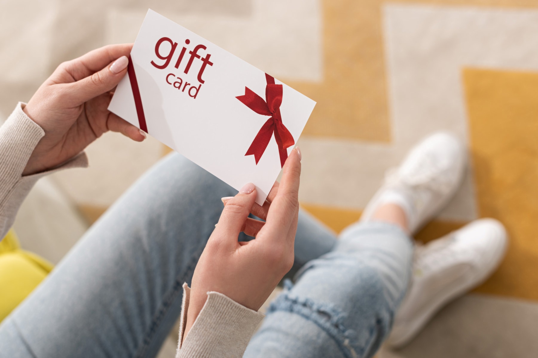 Person holds gift card with red bow on it.