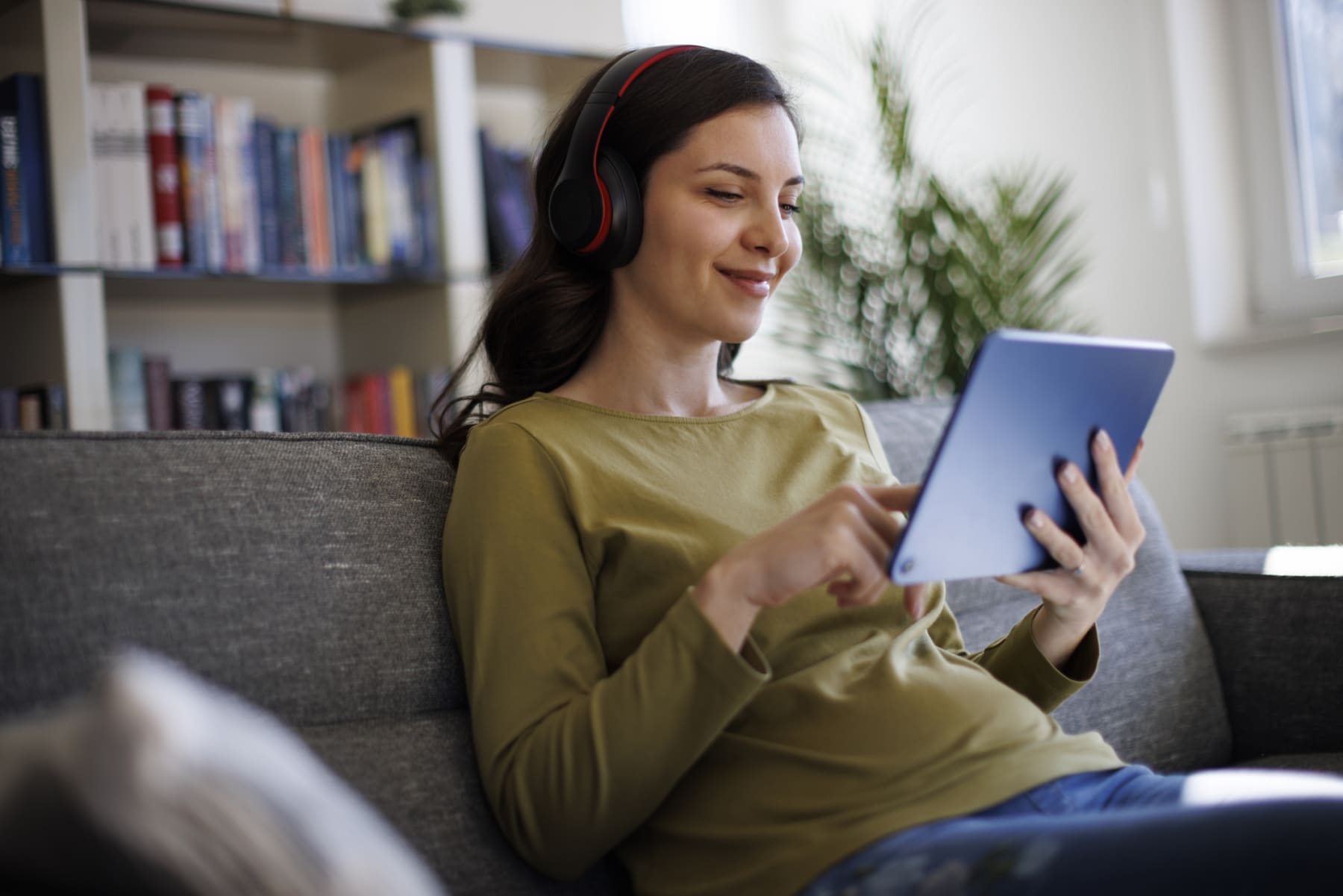 Woman wearing headphones uses tablet.