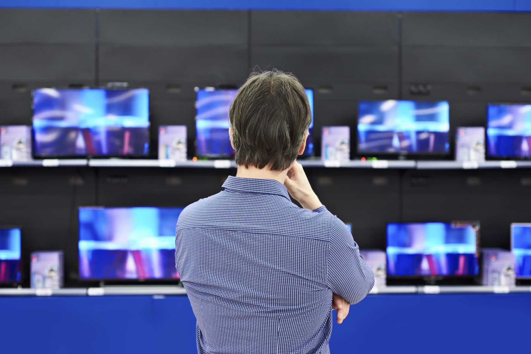Man stands in front of television display.