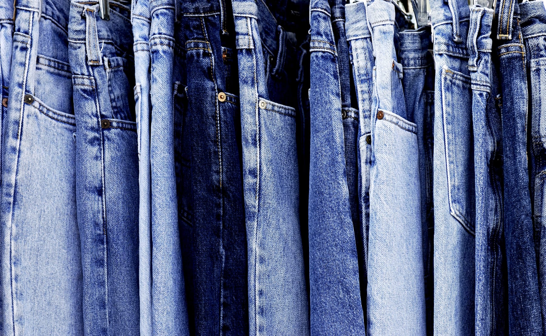 Blue denim jeans hang in row.