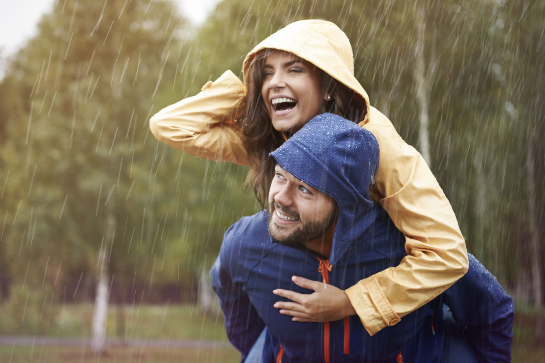 Man gives woman piggyback ride in the rain.